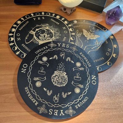8" wooden pendulum grids with engraved Moth, Crystal Ball, and Cauldron designs for divination and energy work.