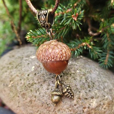 Handcrafted acorn pendant with brass pinecone and acorn charms on a warm brown cord.