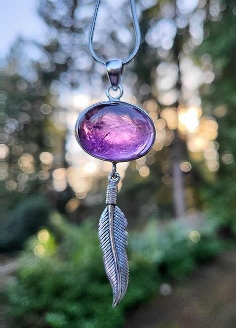 Handmade sterling silver pendant with a 3/4" Amethyst cabochon and silver feather, 2½" long, on an 18" chain.