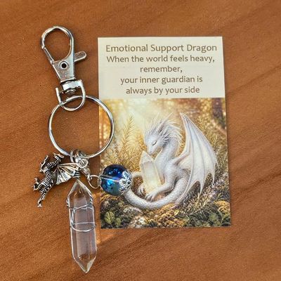 Silver dragon charm with aqua aura bead and clear quartz point beside a card