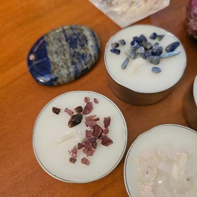Four unscented soy tea light candles topped with gemstone chips displayed on wood