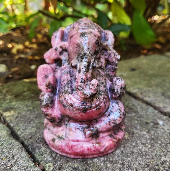 Hand‑carved Rhodonite Ganesh statue with deep pink stone and dark natural contrast.