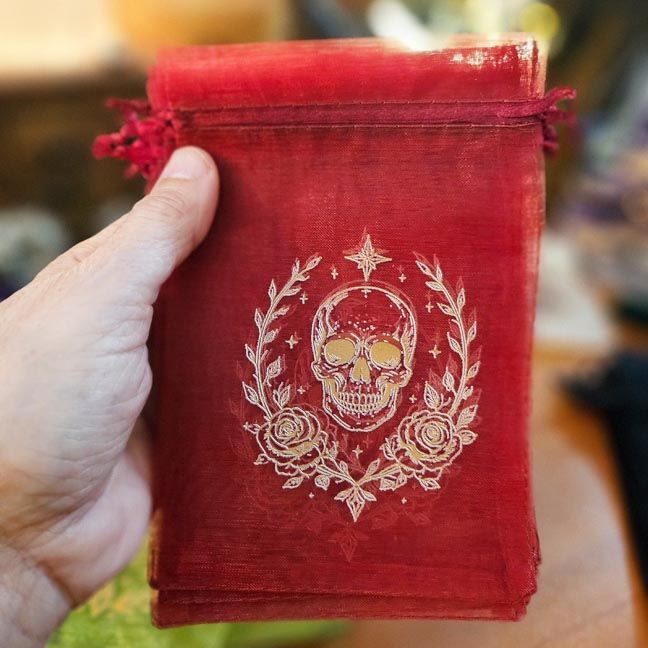 Red organza bag with white skull, roses, and celestial printed design.
