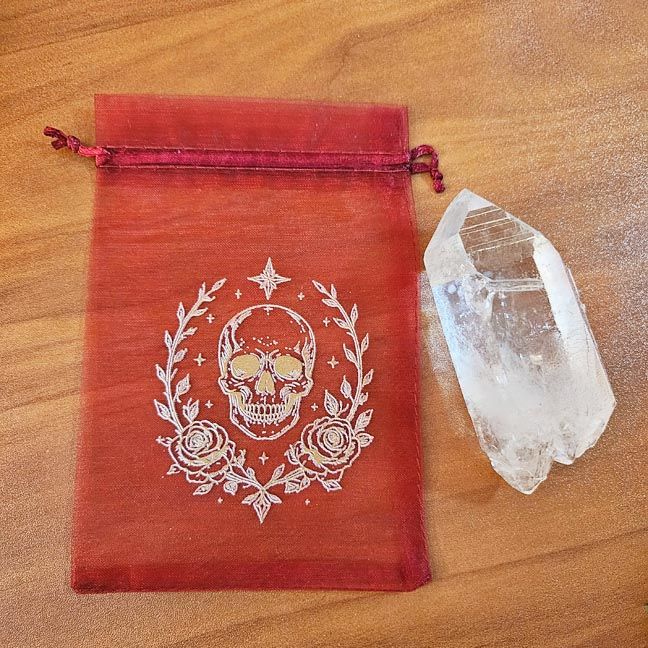 Red organza bag with white skull, roses, and celestial printed design.