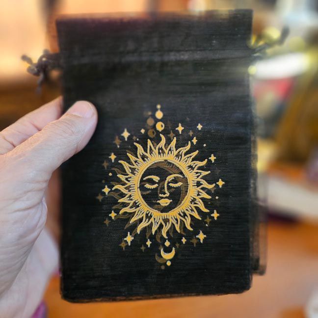 Black organza bag with golden sun surrounded by stars and crescent moons.