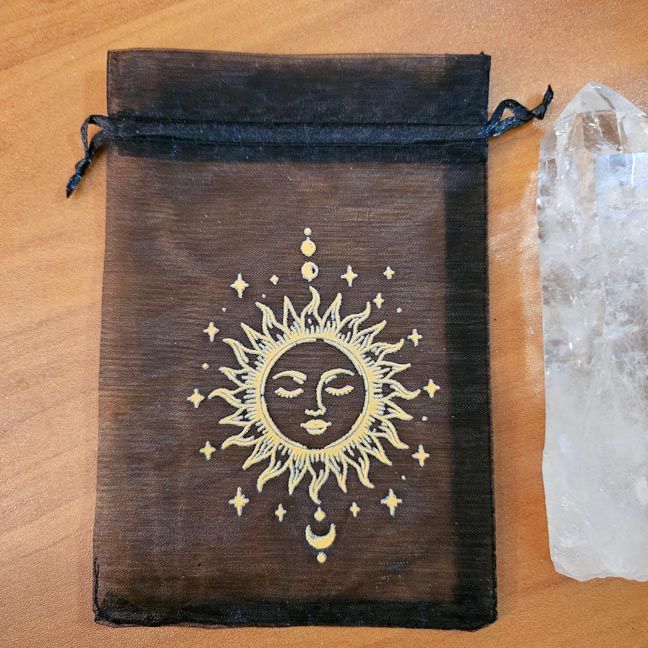 Black organza bag with golden sun surrounded by stars and crescent moons.