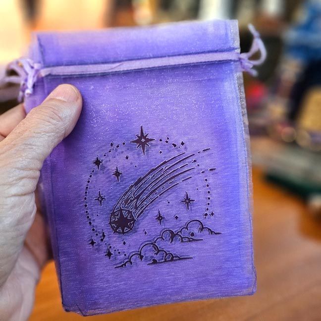Purple organza bag with comet streaking through stars and clouds.