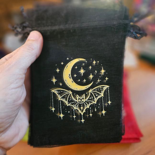 Black organza bag with golden crescent moon, bat, and stars printed design.