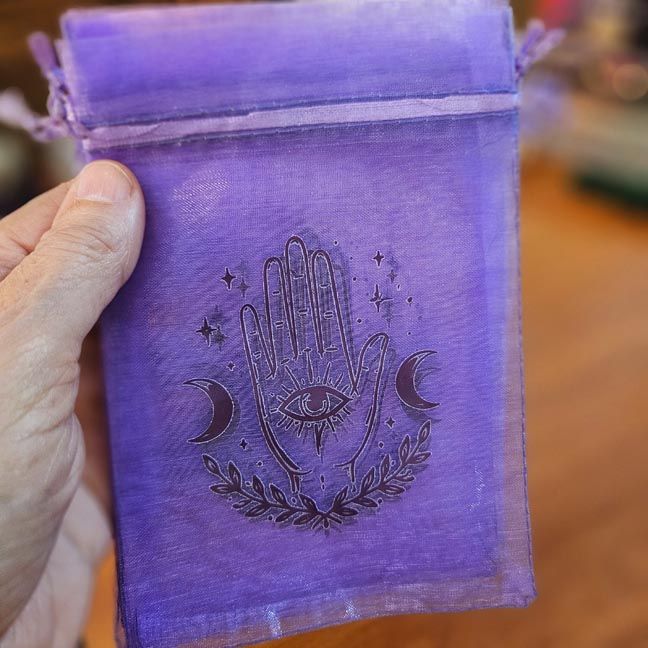 Purple organza bag with protective hand and Evil Eye printed design.