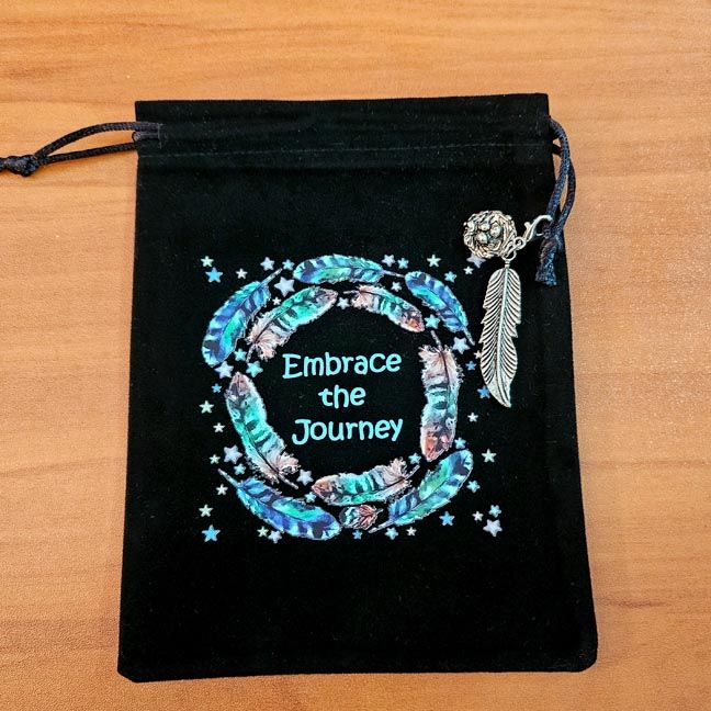 Black velveteen pouch with feather mandala, “Embrace the Journey” text, and silver feather charm.