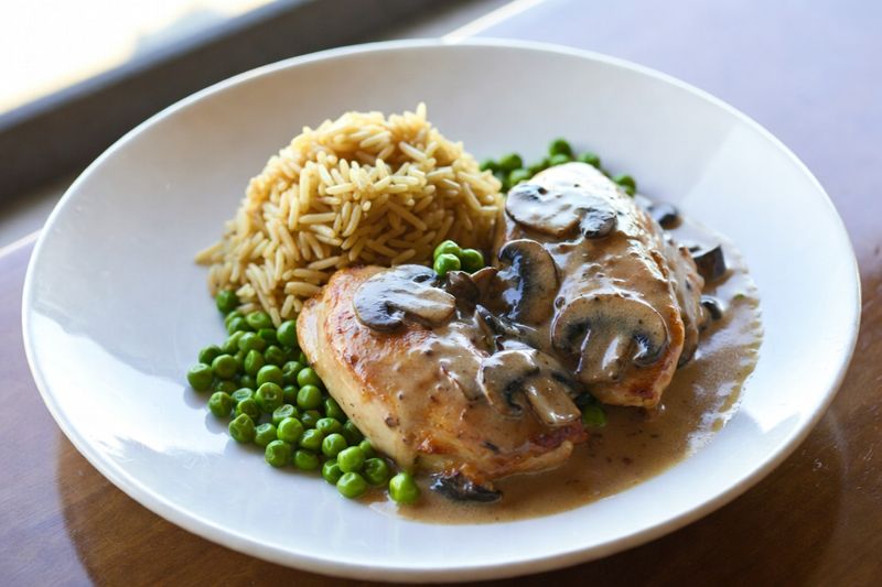 Fricassé de poulet aux champignons accompagné de riz pilaf et petits pois