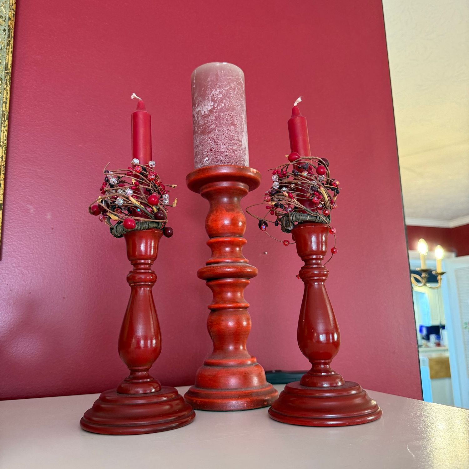 Trio of red wooden candlestick holders and one pillar holder, the tallest is 11"H