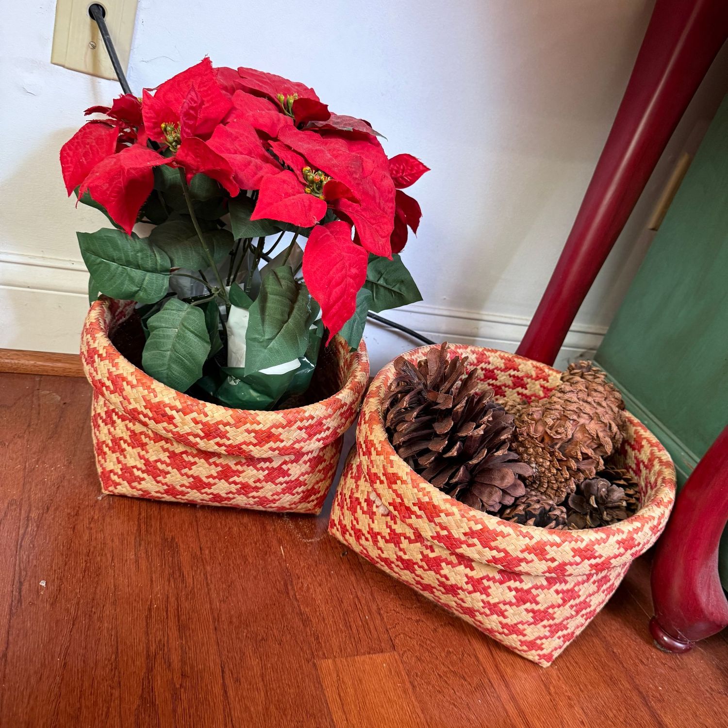 Two tan and red soft woven baskets 14"W, one with a faux poinsettia, the other with large pinecones