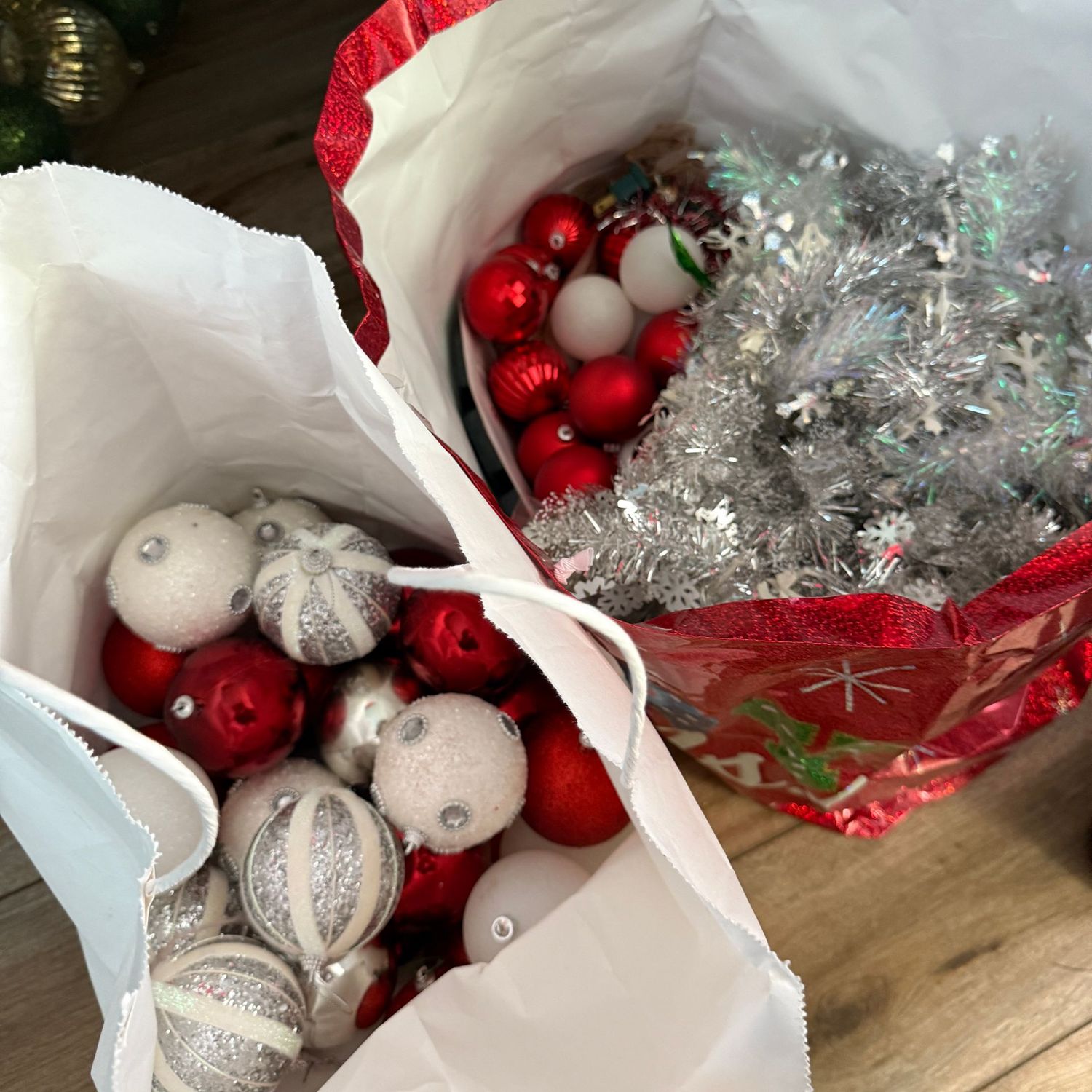 Two gift bags full of red, white and silver ornaments and silver garland