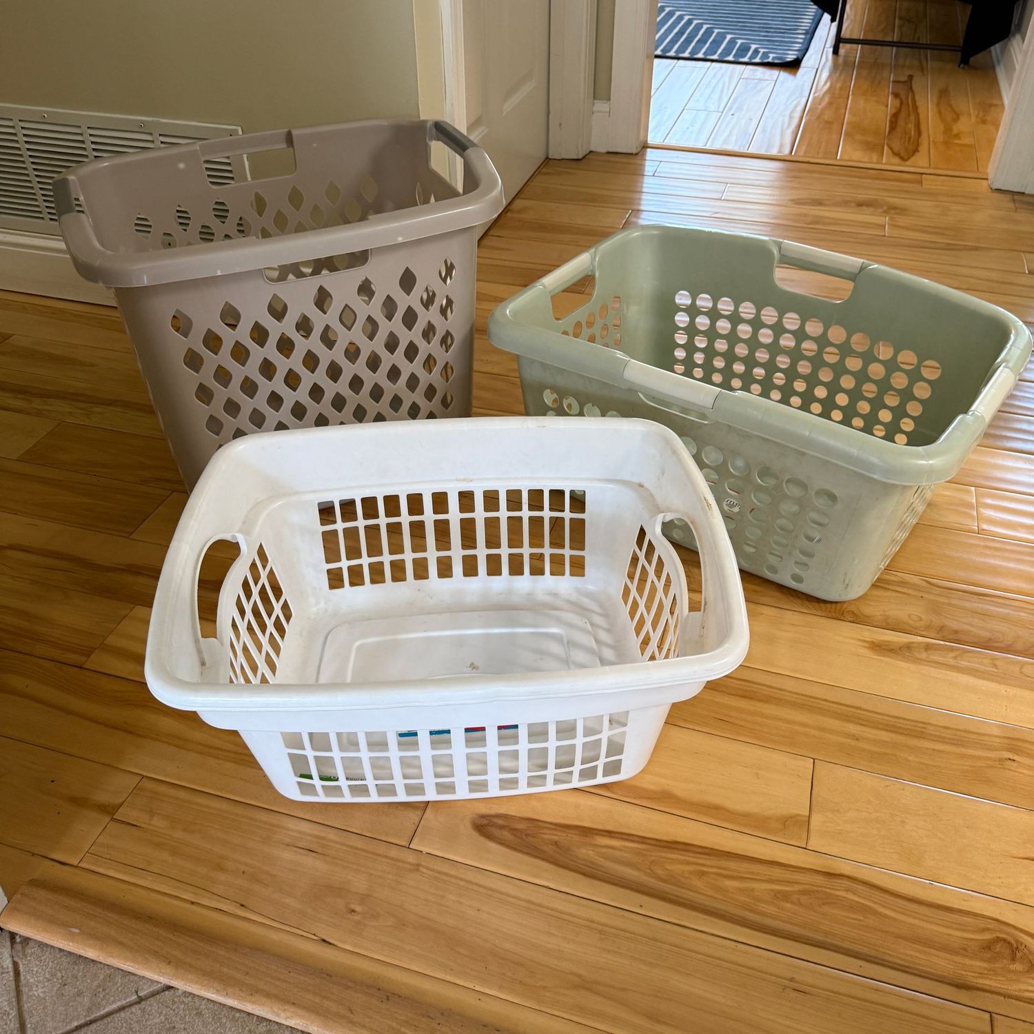 Three plastic laundry baskets, one is taller