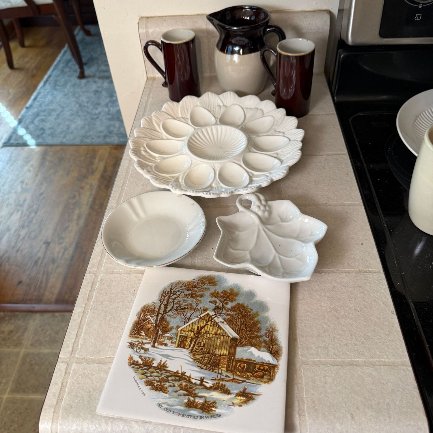 Group of kitchenware with trivet, trinket, and egg dishes, slender mugs, small pitcher
