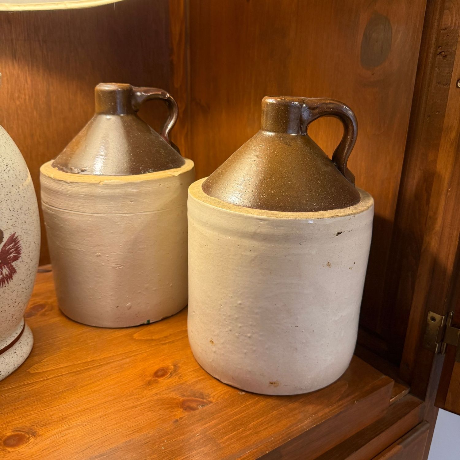 Two brown and tan one-gallon jugs with tapered tops, one has a hairline, minor chips Two brown and tan one-gallon jugs with tapered tops, one has a hairline, minor chips