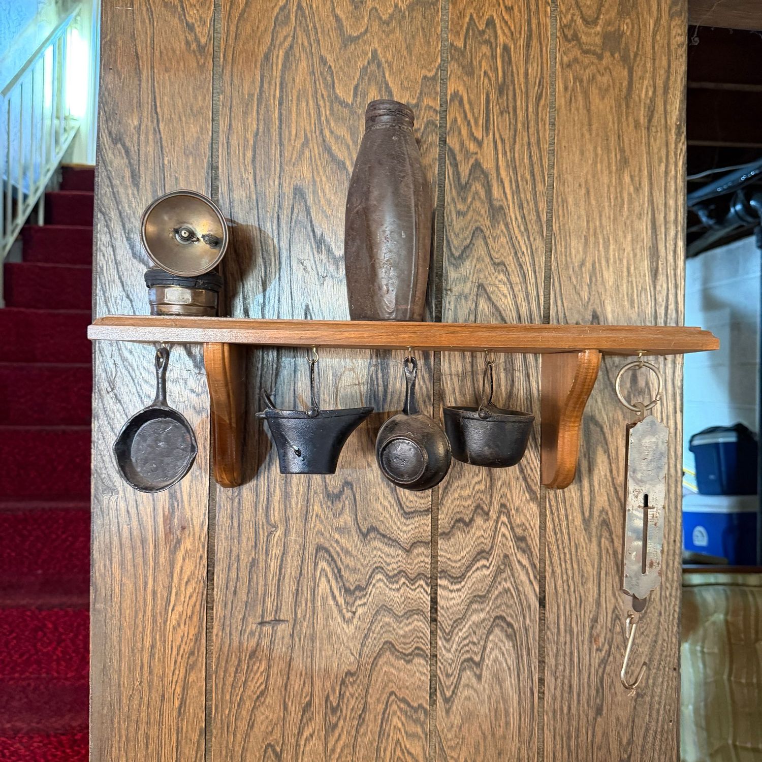 Shelf with miner's lamp, metal bottle, scale, and small cast iron pots and pans