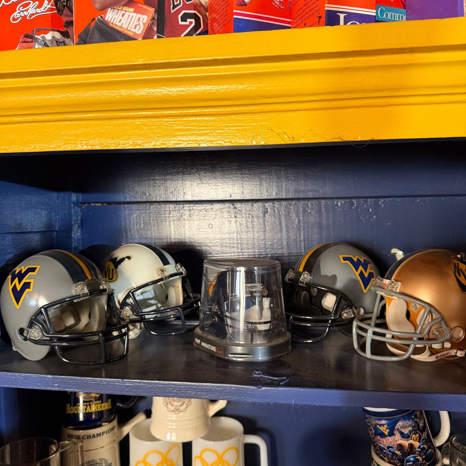 Group of five WVU miniature football helmets, four are 5" (one has a sticker that needs glued), one is in package and is about 4.5"