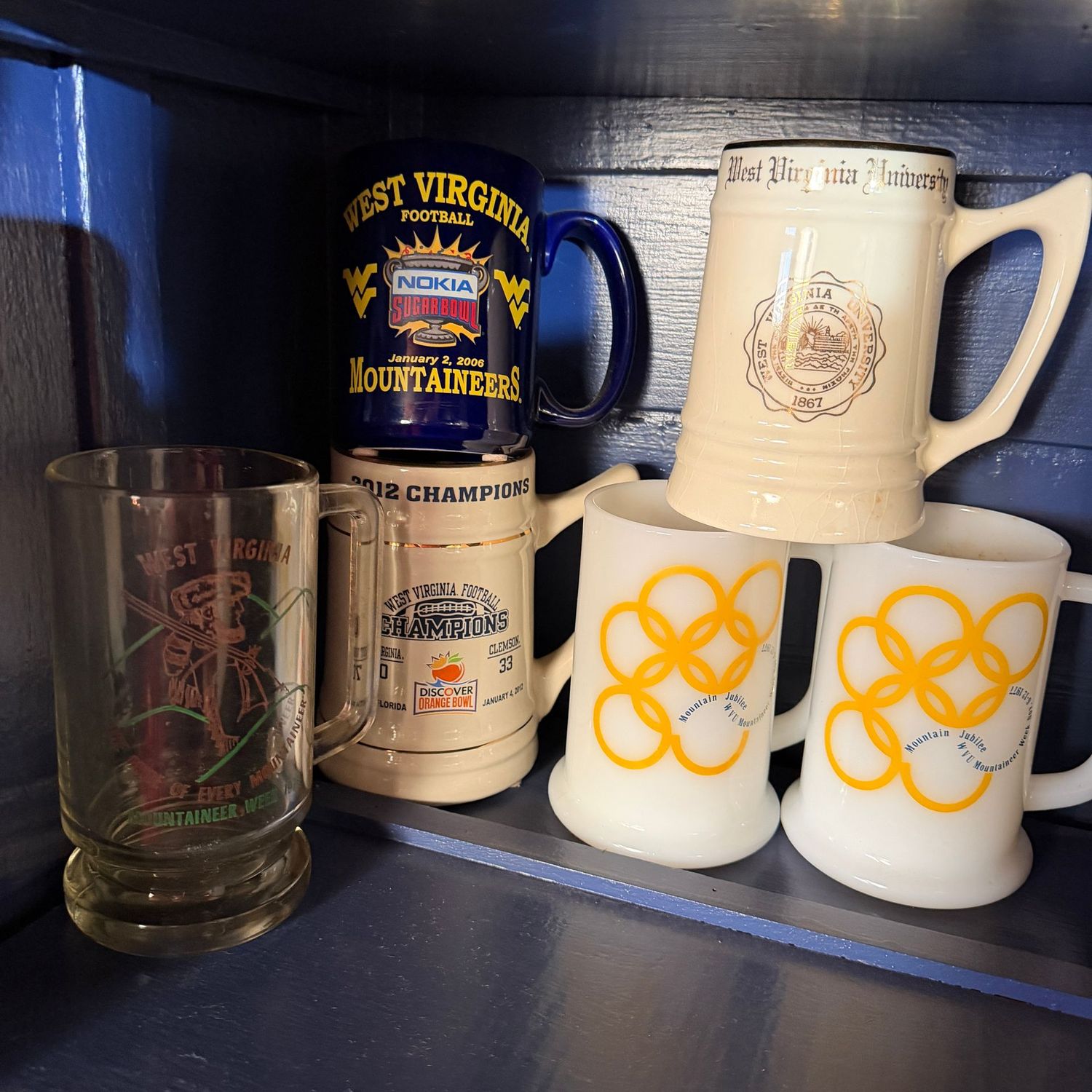 Group of WVU mugs, including Mountain Jubilee and Discover Orange Bowl