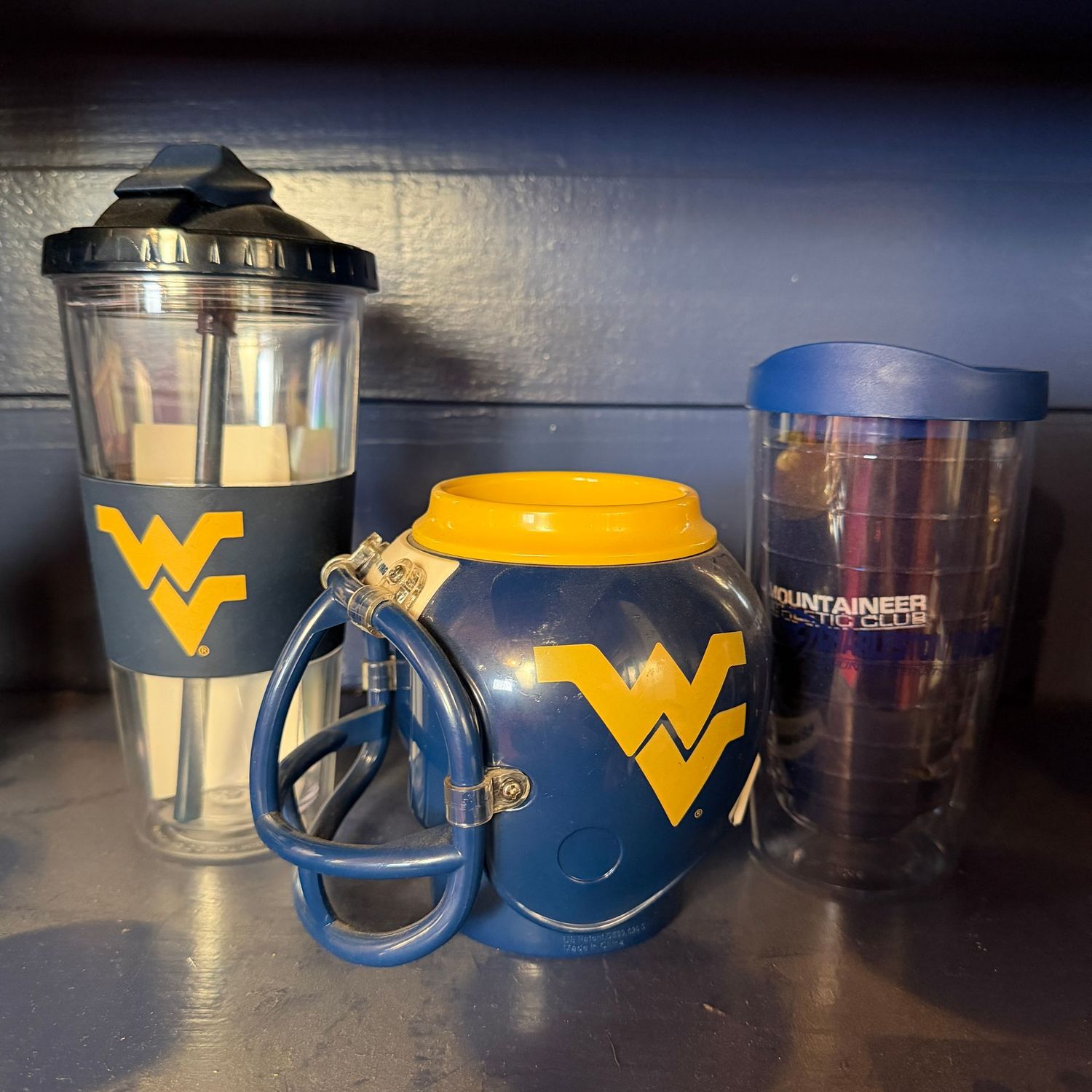 Group of WVU plastic drink cups, 2 travel mugs appear unused, helmet cup