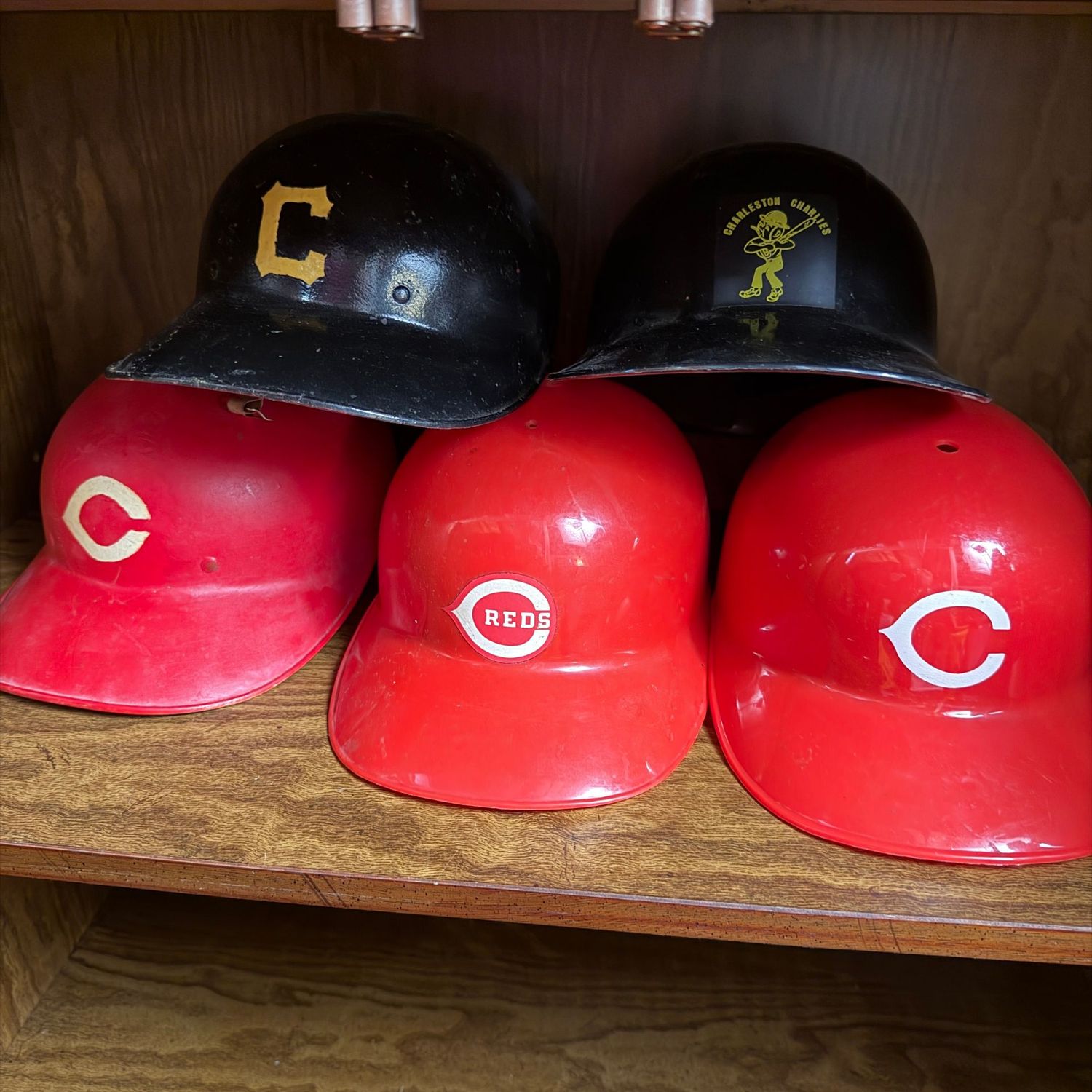 Group of vintage baseball helmets, including Cincinnati Reds and Charleston Charlies