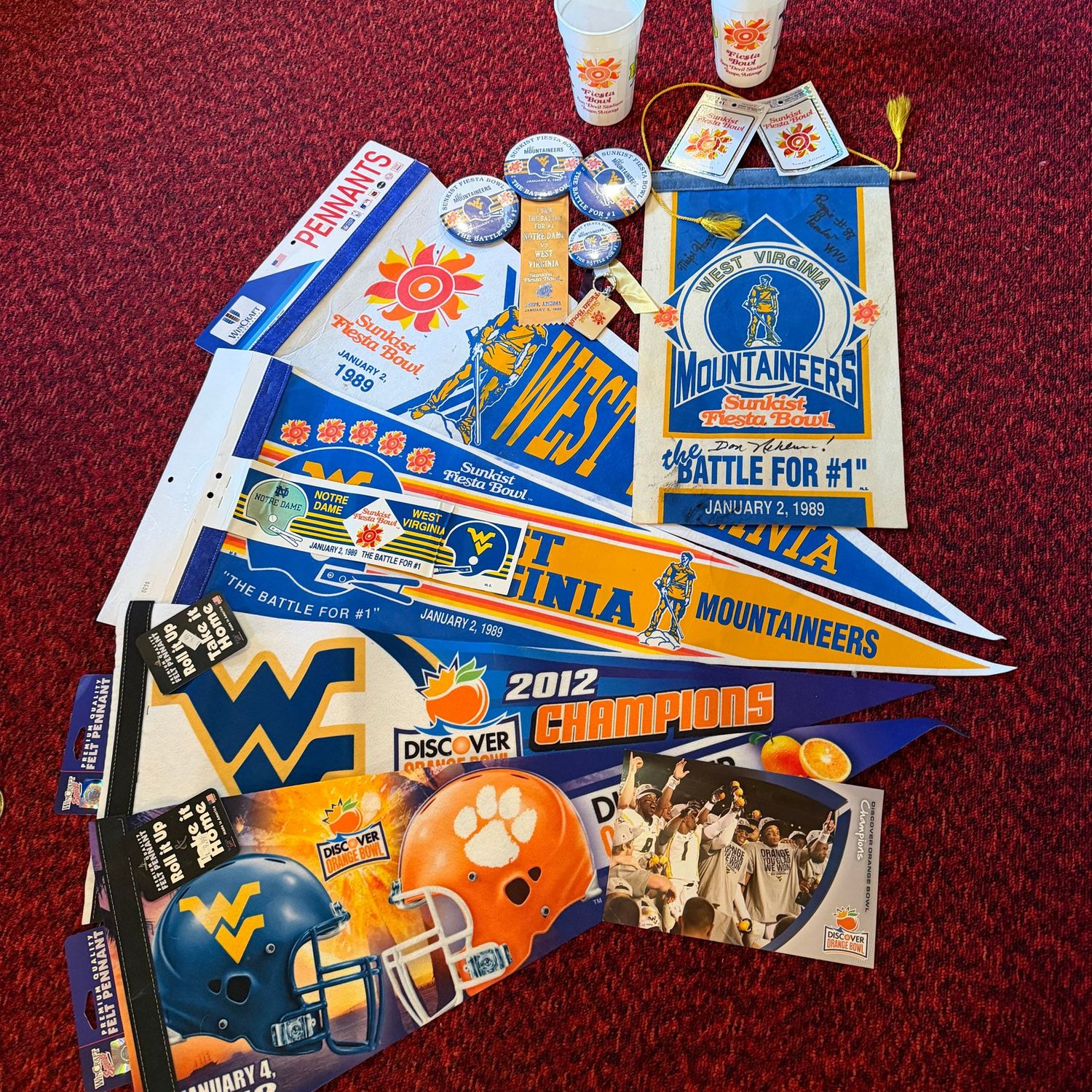 Sports Memorabilia Lot C with WVU Orange & Sunkist bowl pennants, Sunkist bowl buttons, and signed 1989 felt Sunkist Fiesta Bowl banner (a few spots) by Major Harris, Reggie Rembert & Don Nehlen