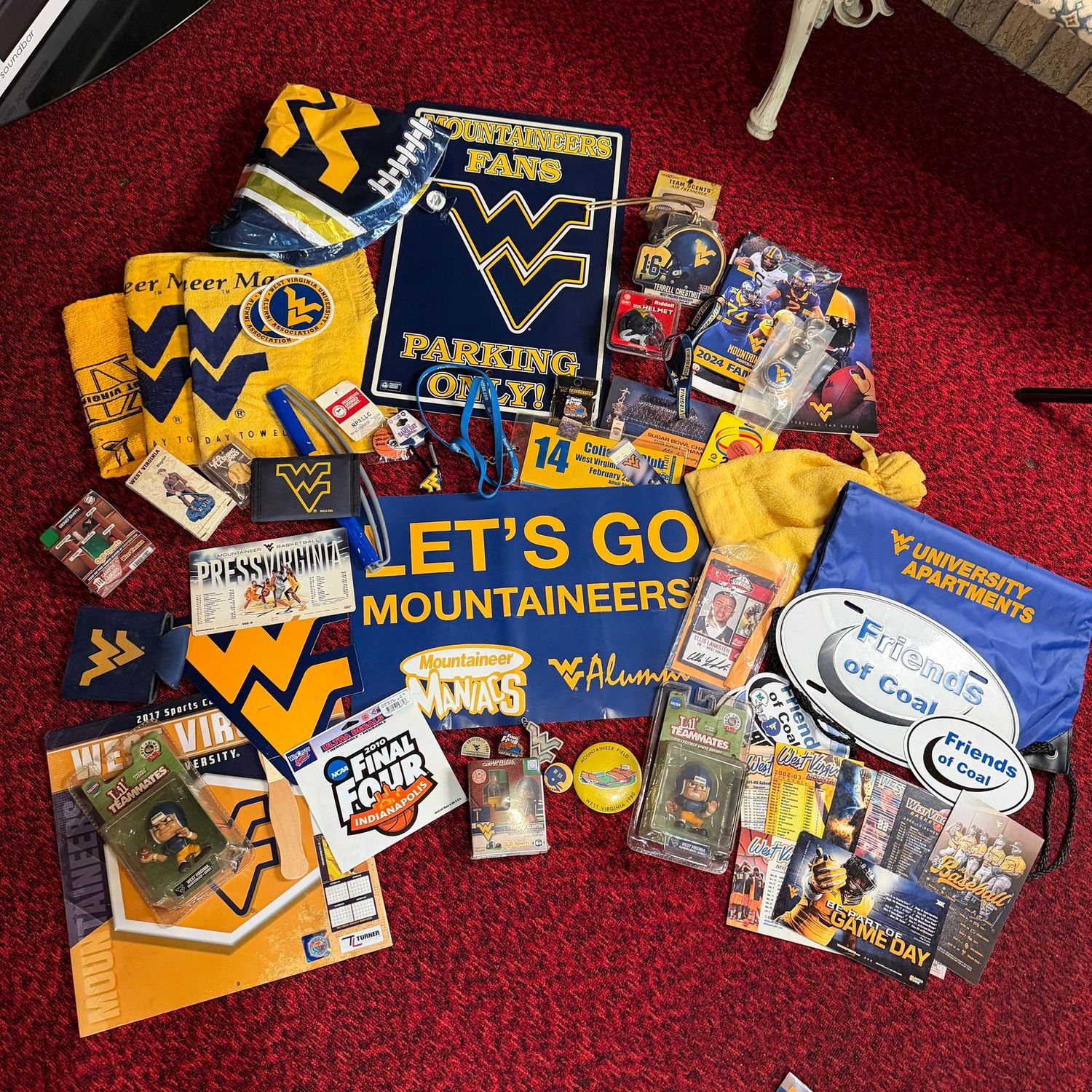 Sports Memorabilia Lot E, including WVU pins, buttons, towels, banners, calendars, a large plastic parking sign, stickers, and small trinkets