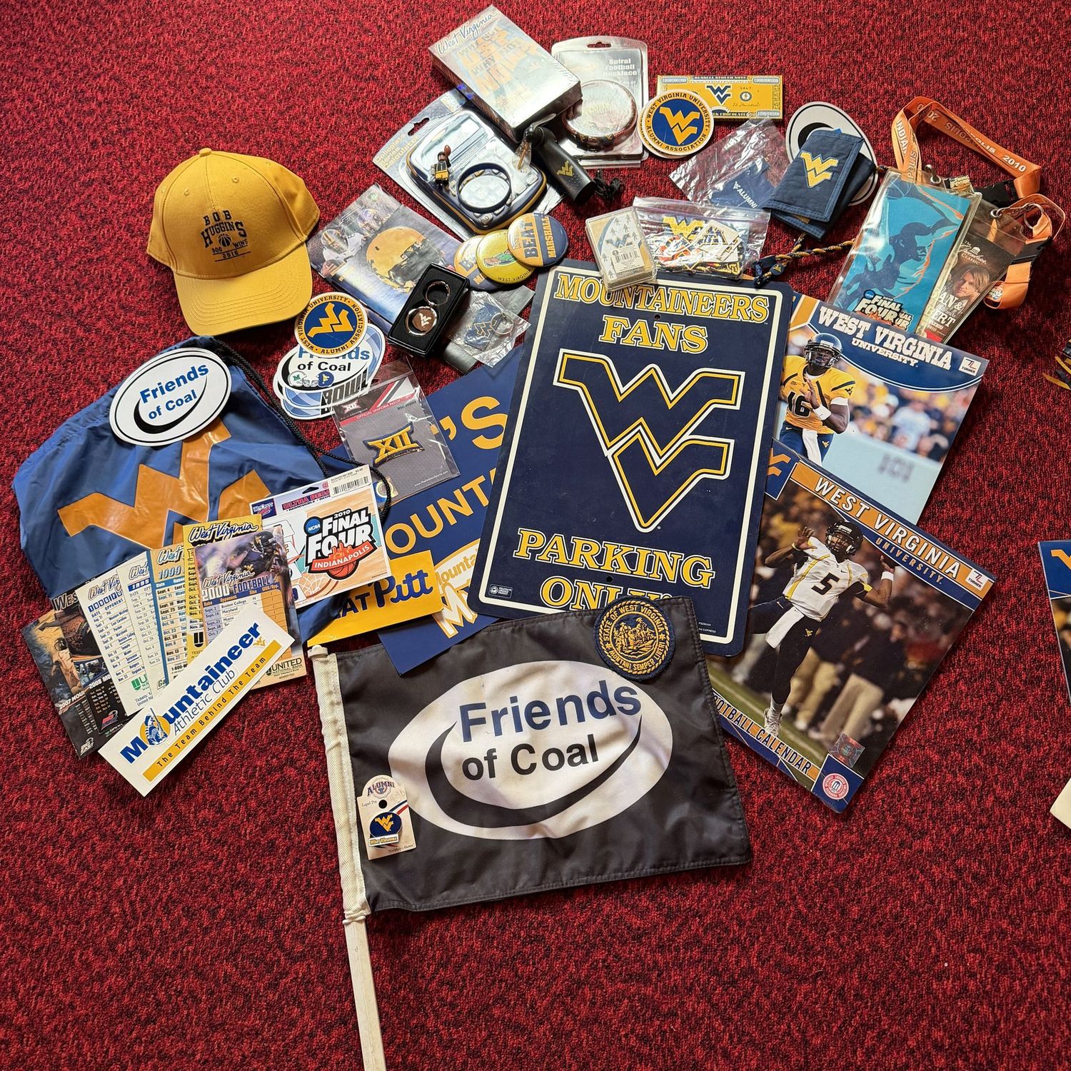 Sports Memorabilia Lot H, including WVU parking sign, hat, stickers, pin, buttons, patches, bracelet, stickers, calculator, key chains, game tickets, and more