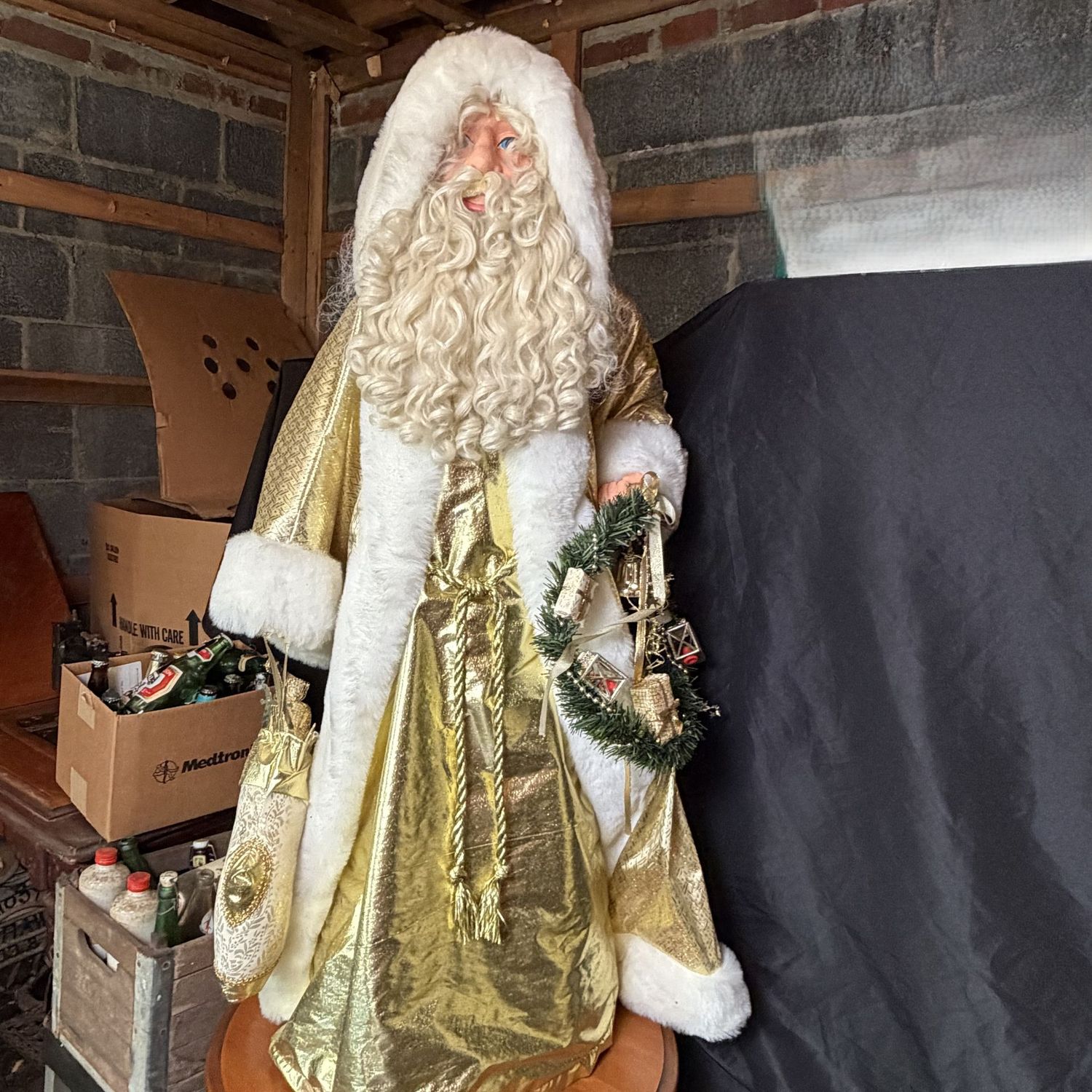 Tall Santa decoration with curly beard, gold outfit, holding a stocking and wreath, plastic cone base, 48"H