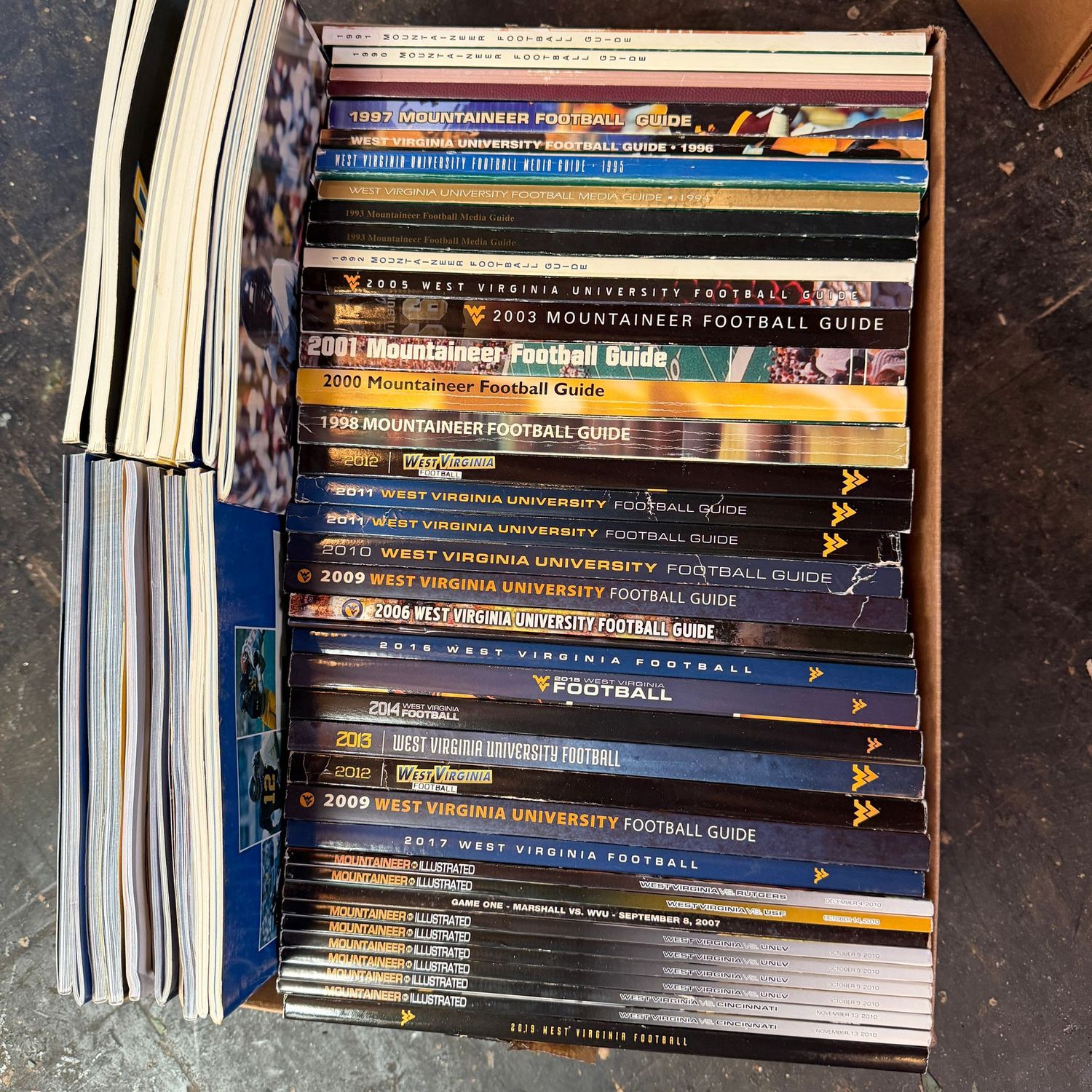 WVU/Sports Ephemera Box #10 Mountaineer Illustrated and season guides, some dating back to the 1980s (This item is heavy & in the lower level)