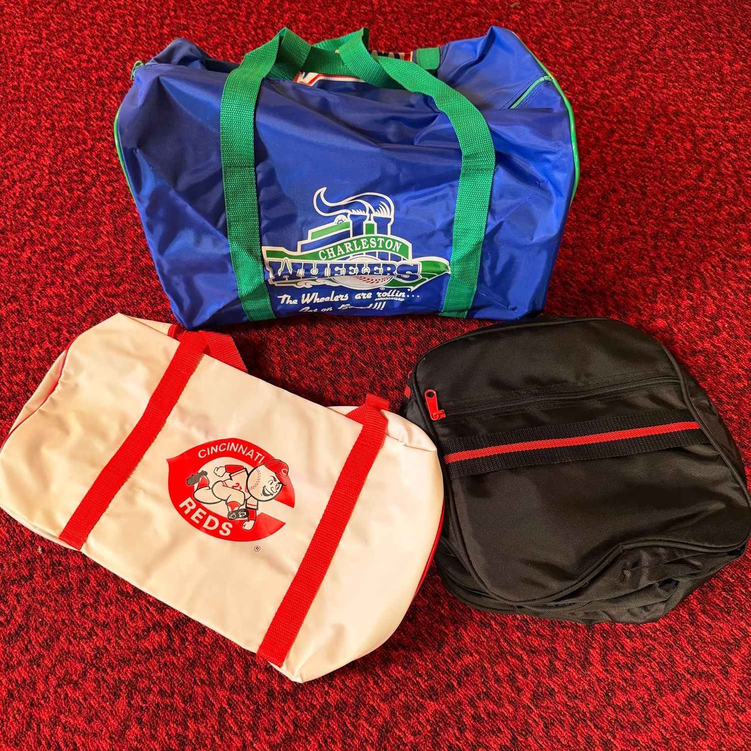 Group of 3 new small gym duffle bags, Charleston Wheelers, Cincinnati Reds, and a black & red, 15-17"