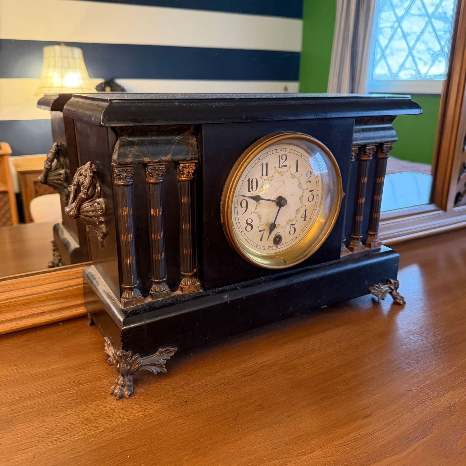 Vintage black clock with pillars, overall good condition of case, ticks but does not chime, not tested for accuracy, 10"H x 14"W