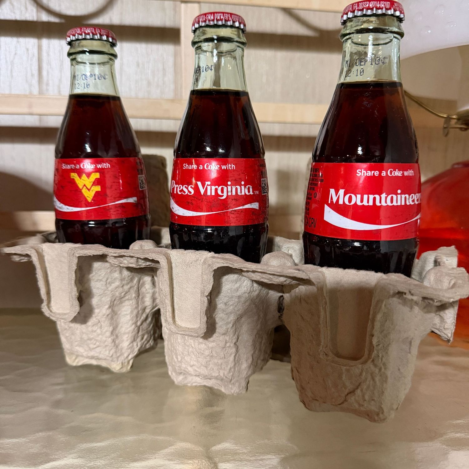 Three WVU logo Mountaineer Coca-Cola bottles, filled