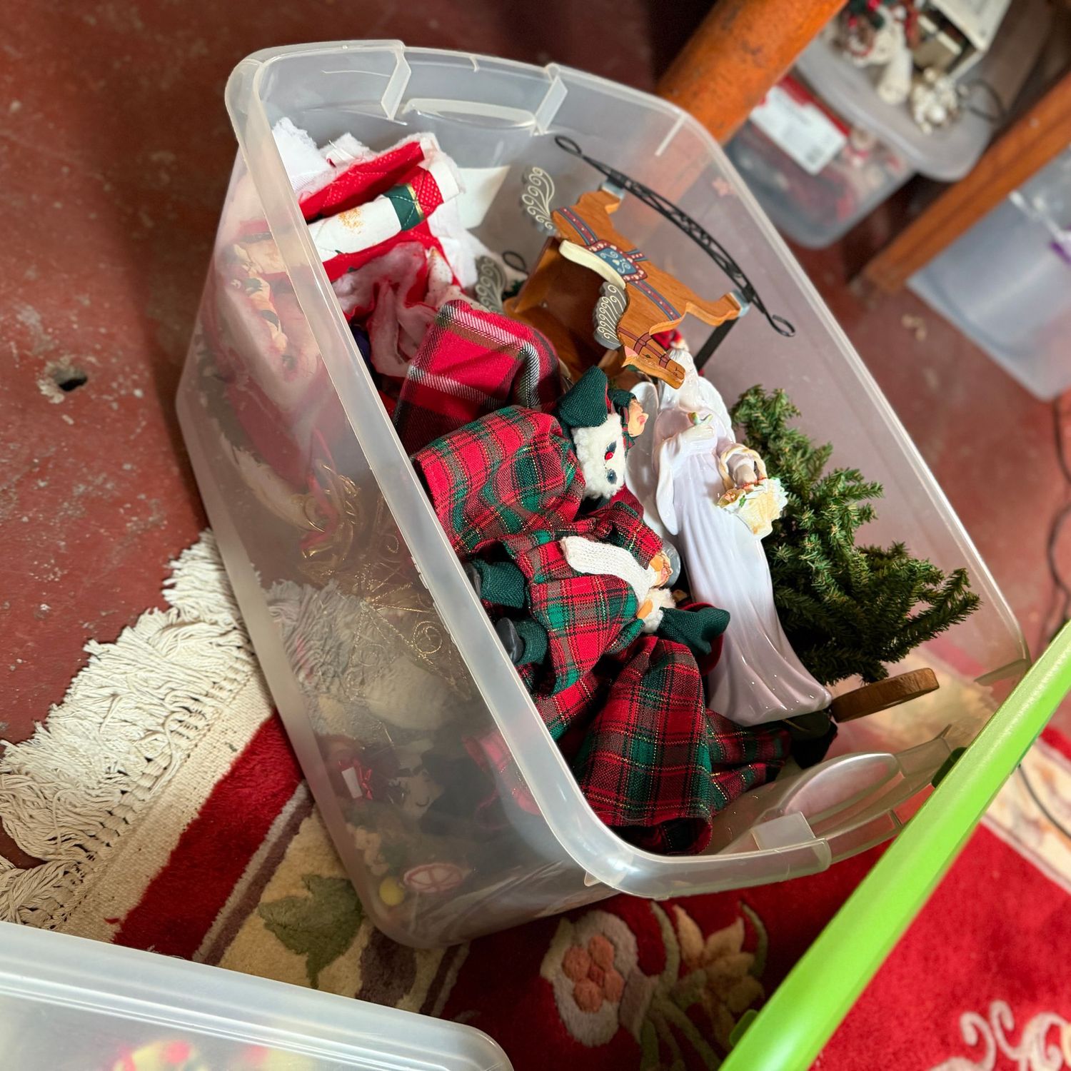 Clear bin with lid filled with cloth-body carolers, ceramic angel, & more