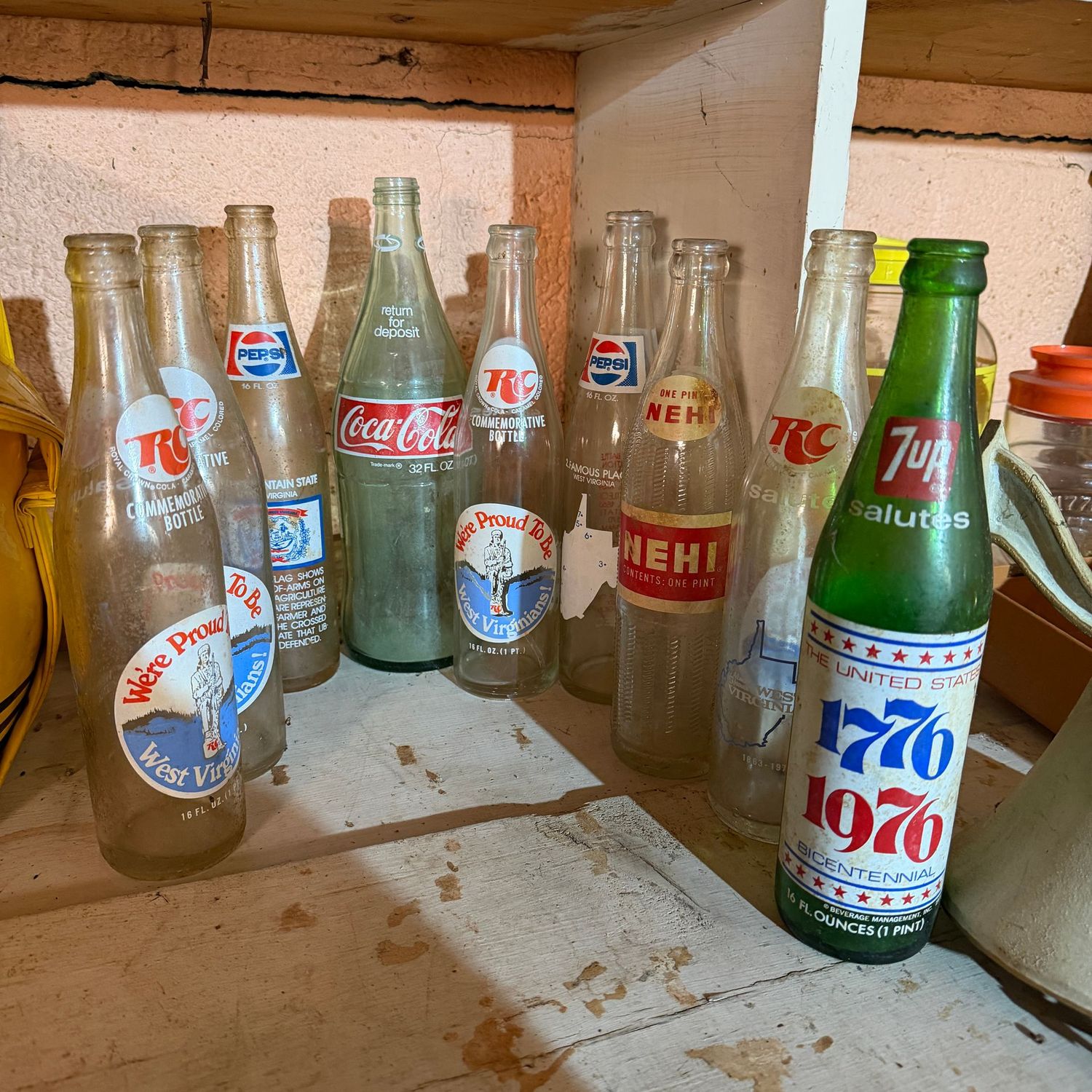 Group of empty vintage pop bottles including RC, Coca-Cola, and Nehi