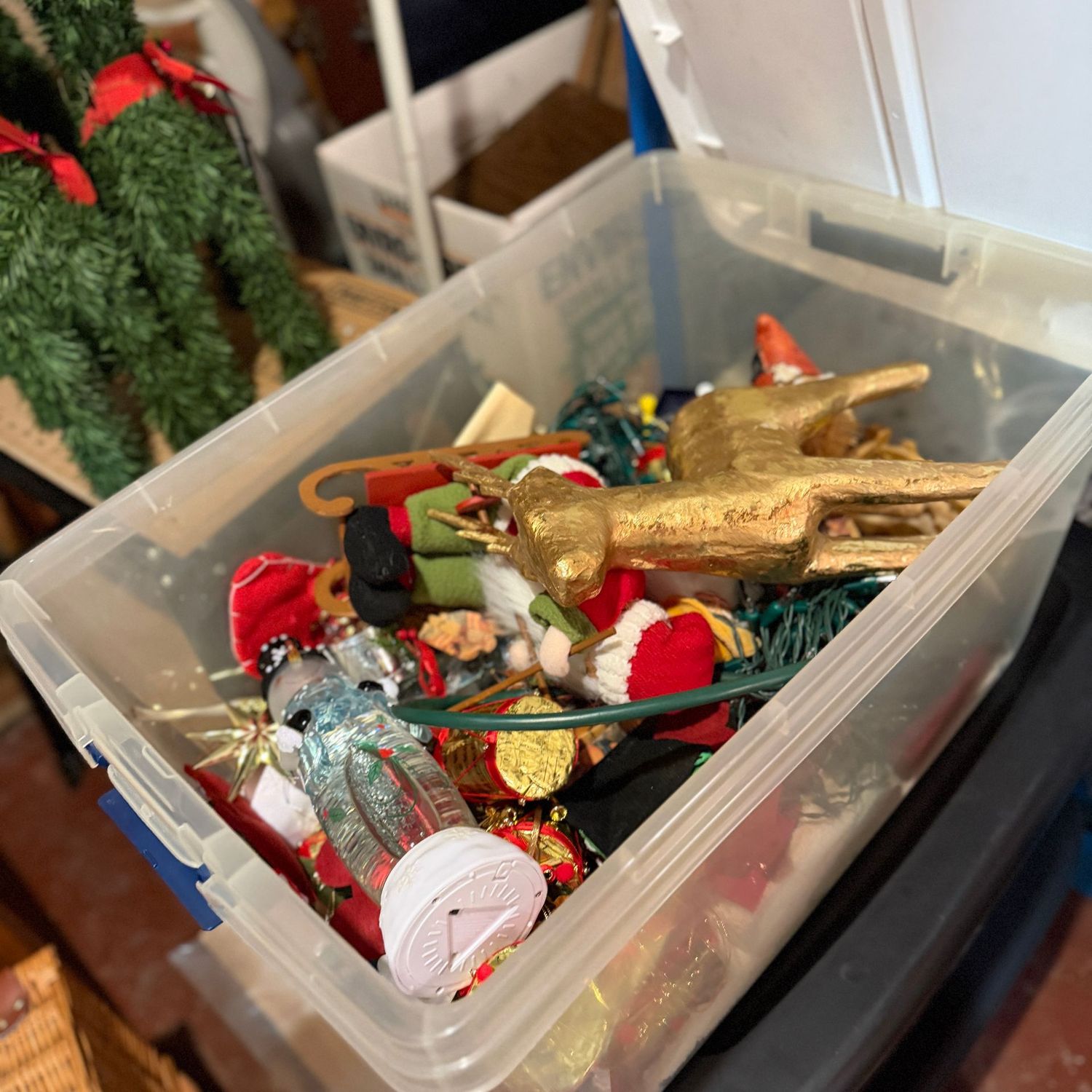 Clear mystery bin with lid of Christmas decorations, mache reindeer, ornaments, and lights