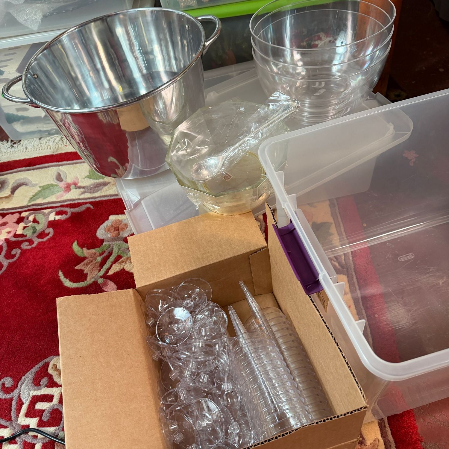 Clear large bin with lid with drink bucket, serving bowls, and plastic champagne glasses