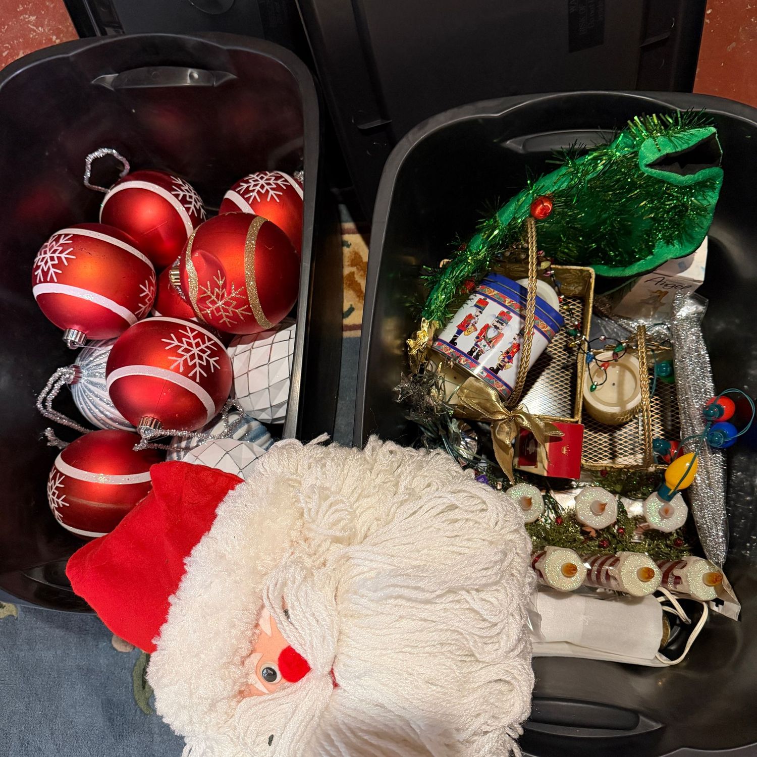 Two black bins with lids filled with Christmas decorations