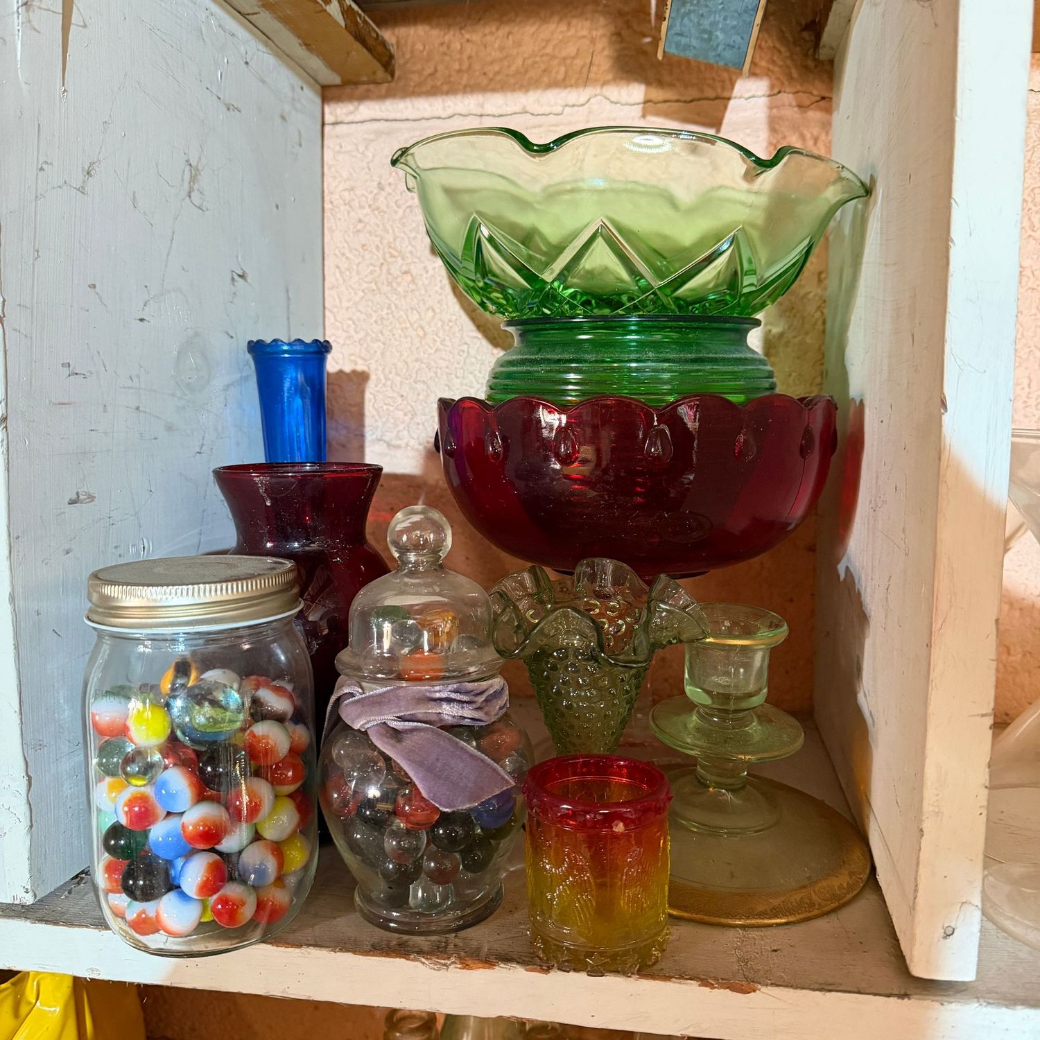 Shelf of colorful vintage glassware and marbles