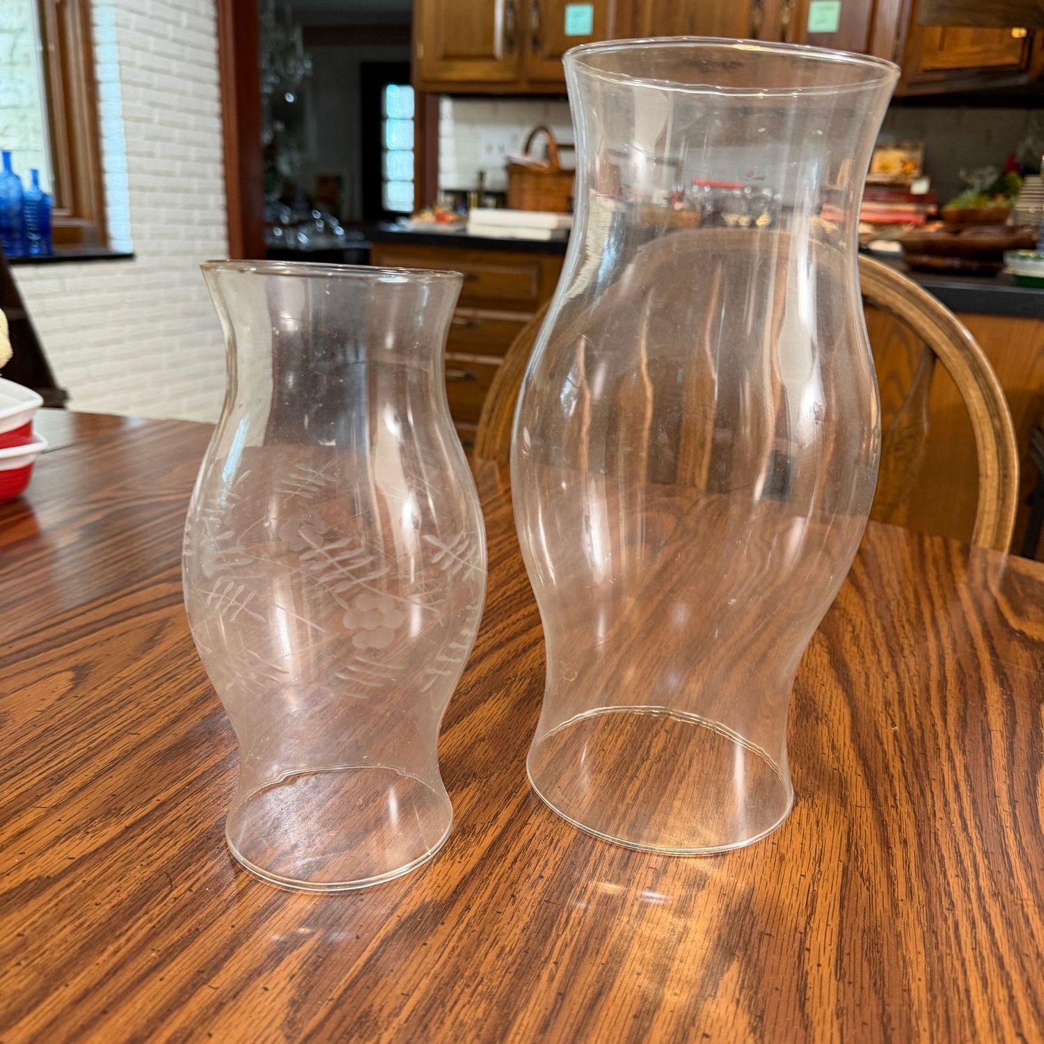 Two glass candle chimneys, one is etched, the tallest is 11 Two glass candle chimneys, one is etched, the tallest is 11"