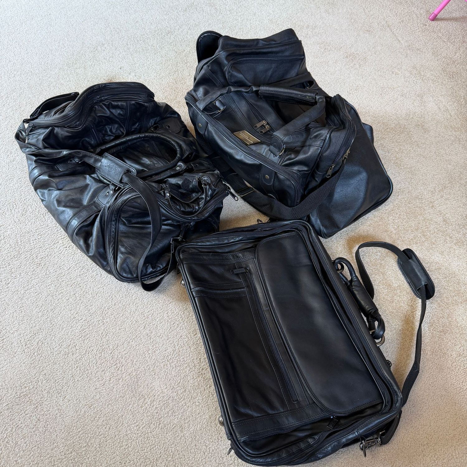 Trio of black travel bags, all leather or leather-like, roomy attache bag, one St. Francis duffel, one Mark Phillip (approx. 18"L)