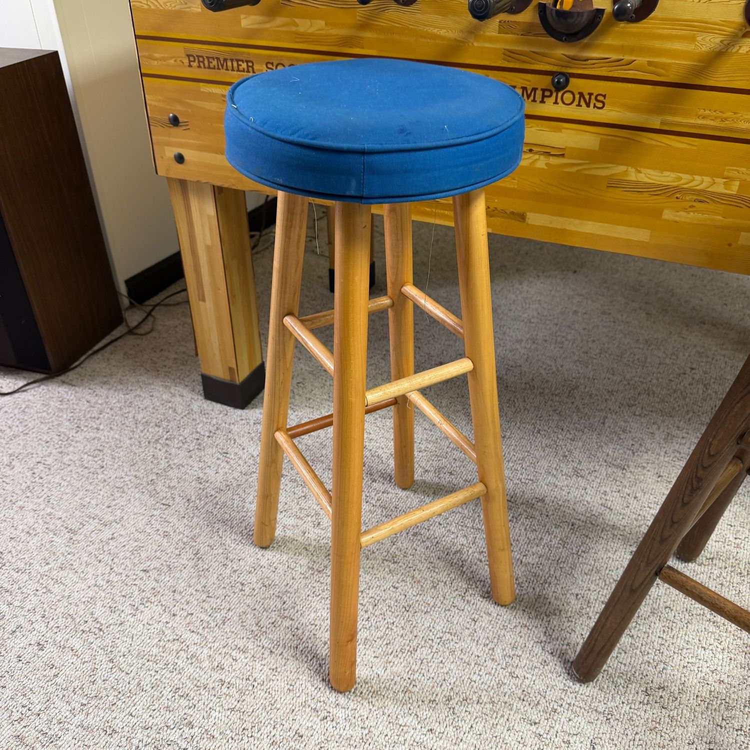 Stool with blue fabric cushion and light wood legs, 30 Stool with blue fabric cushion and light wood legs, 30" x 11"