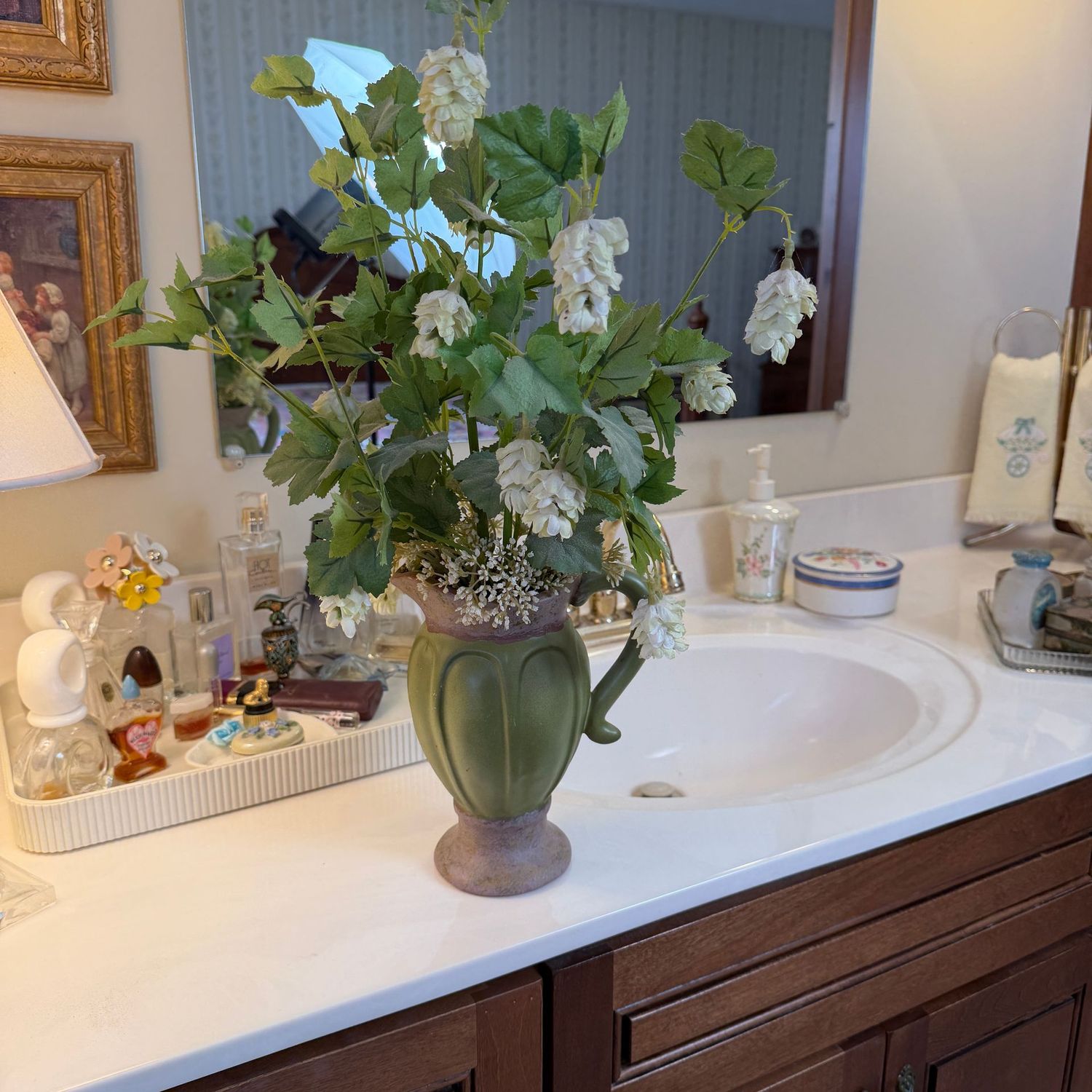Green and brown pottery pitcher with white flower and leafy arrangement, the pitcher is 9"H