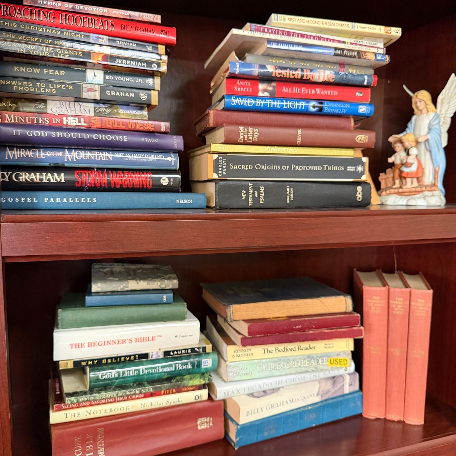Two shelves of spiritual books and angel figurine