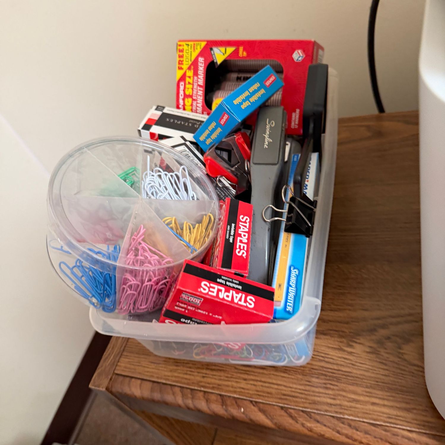 Plastic shoebox of office supplies, stapler, tape, staples, paperclips, binder clips, markers