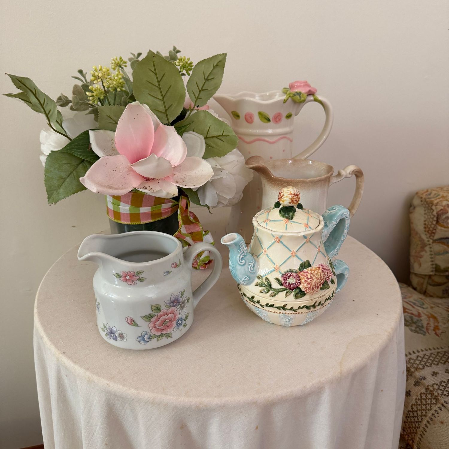Group of ceramic pitchers, teapot, and floral arrangement