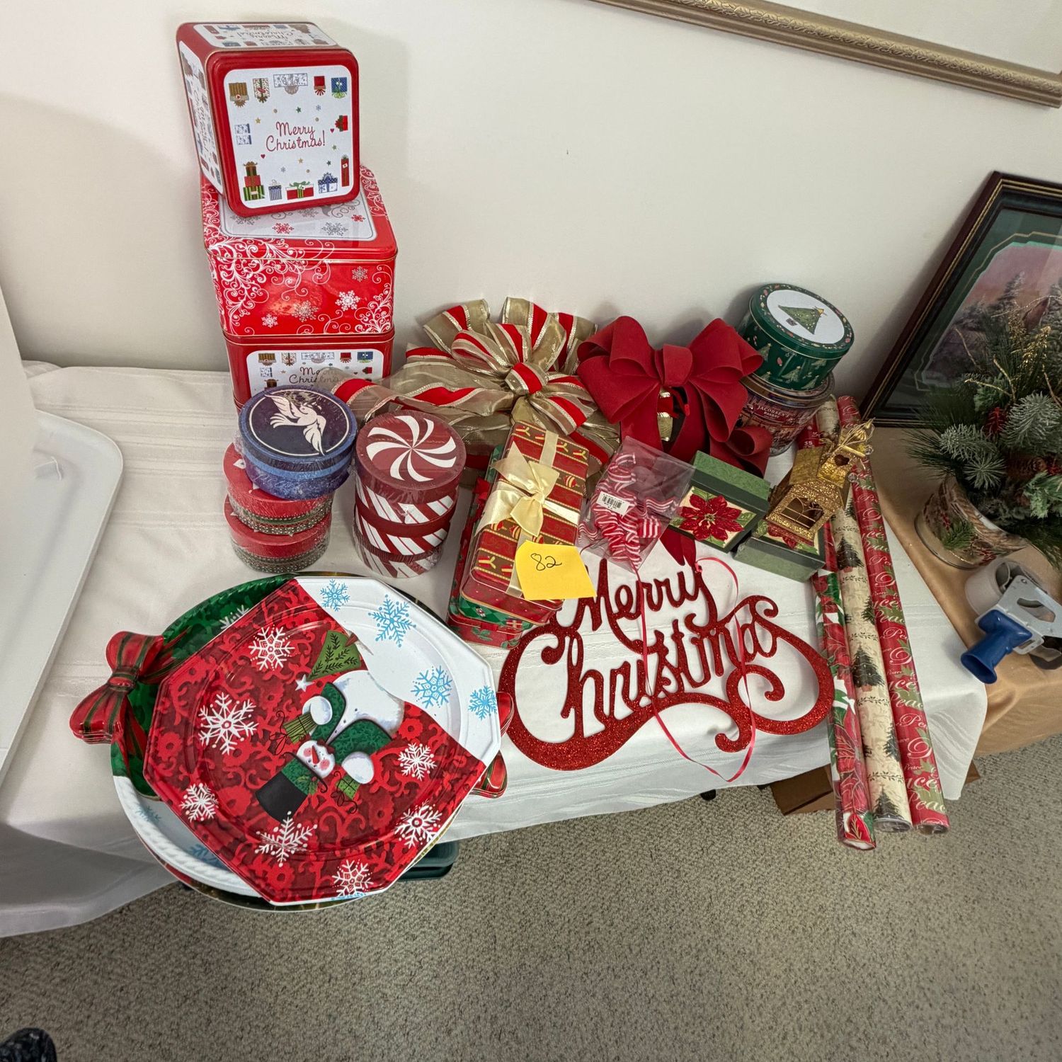 Lot #82, bin of Christmas tins, round boxes, plastic platters, candy ribbon ornaments, bows, wrapping paper