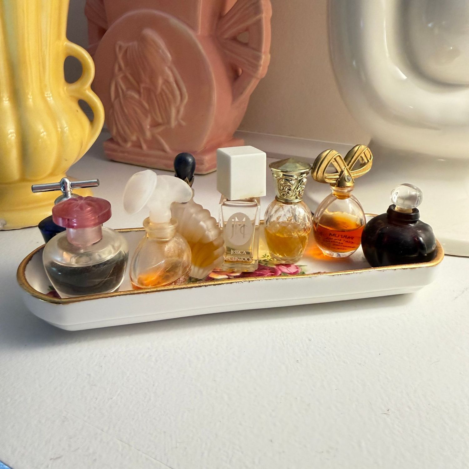Collection of mini perfume bottles on oval ceramic tray