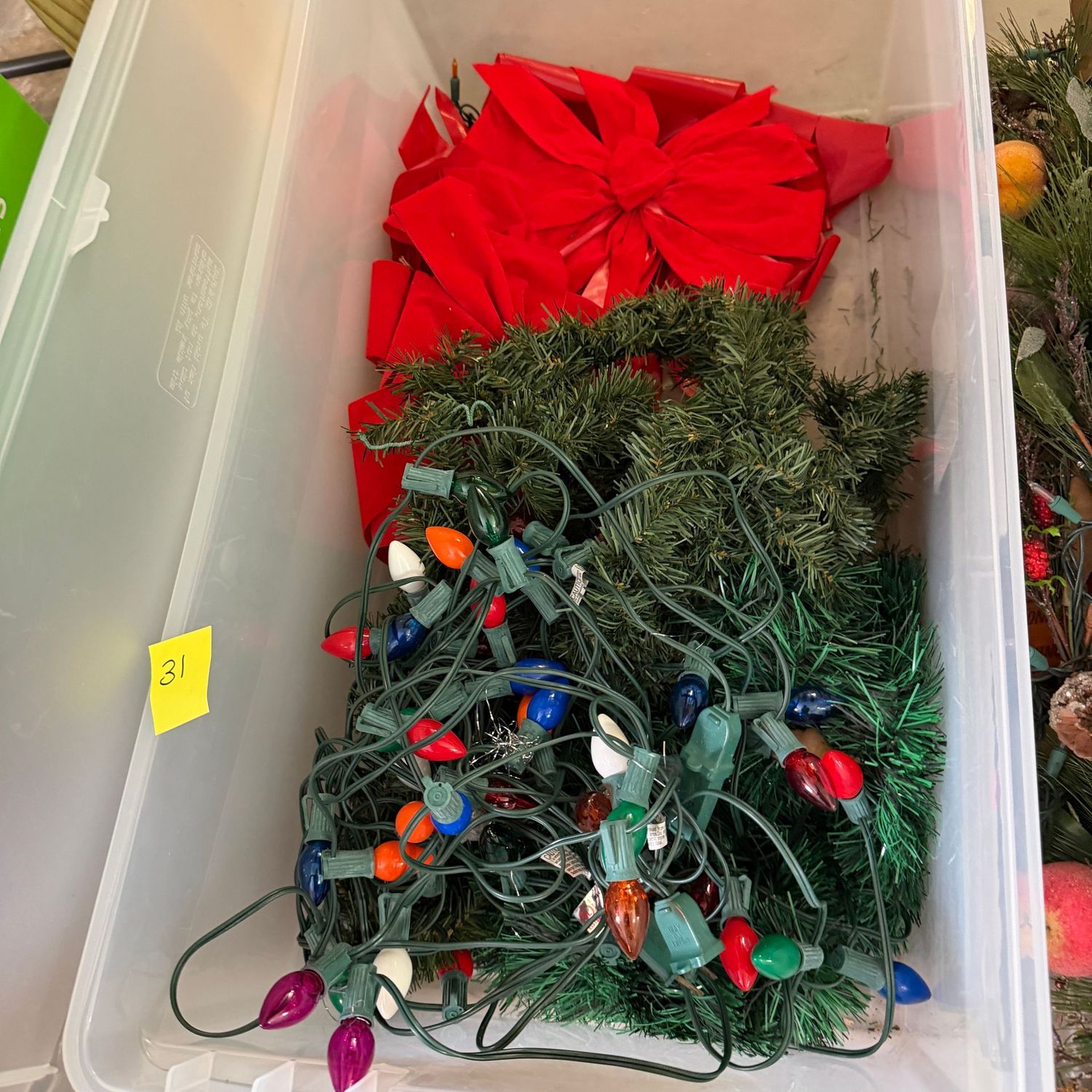 Lot #31, long bin with garland, red bows, large-bulb lights (working)